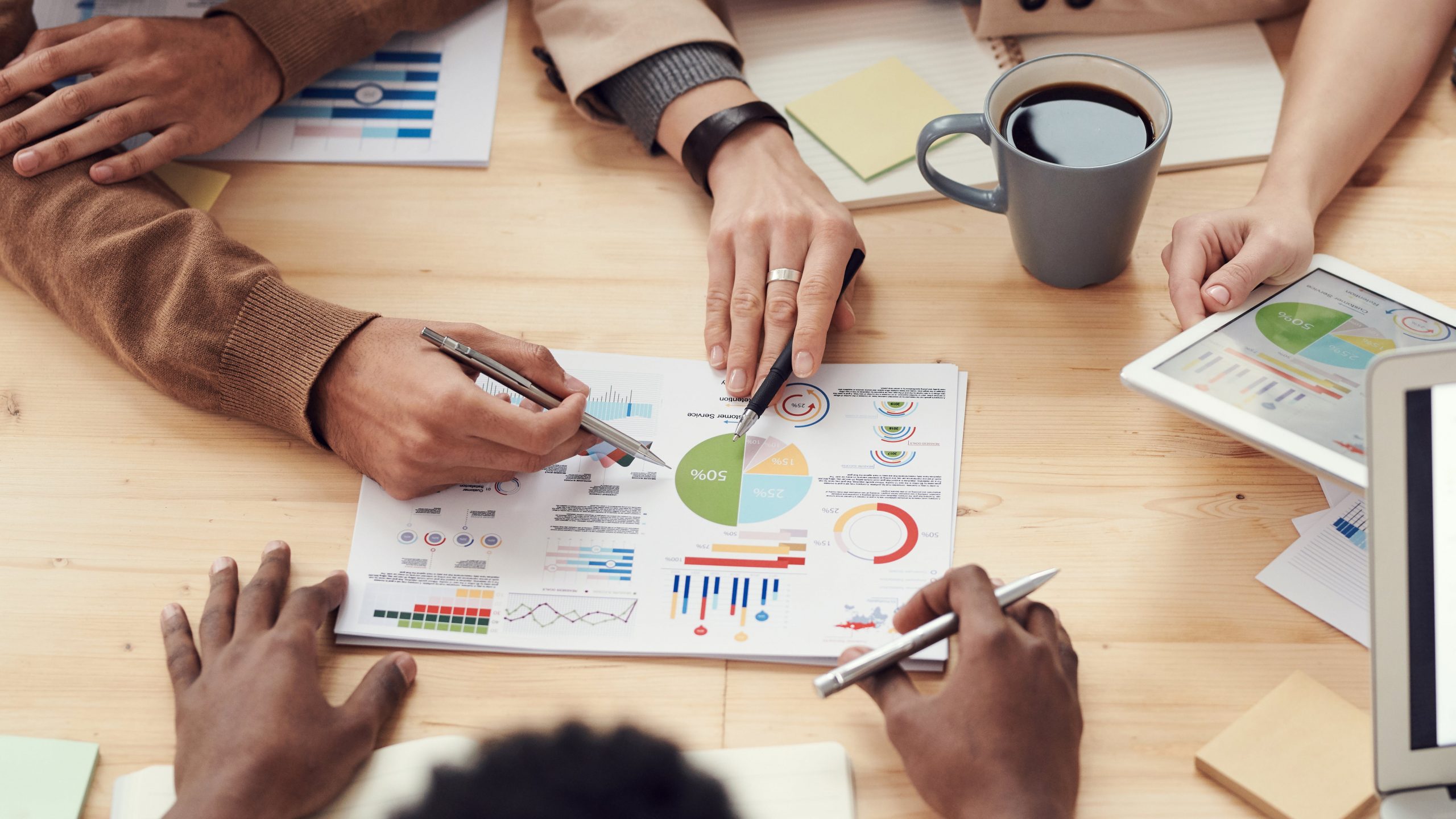 hands pointing a graphs and charts on a paper