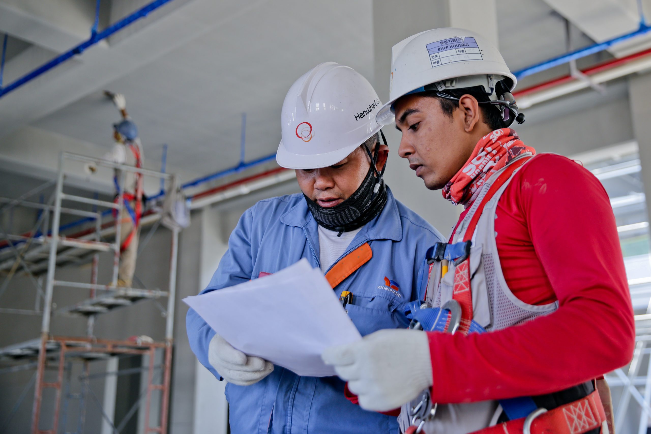 two men with hard hats looking at a document on a construction project