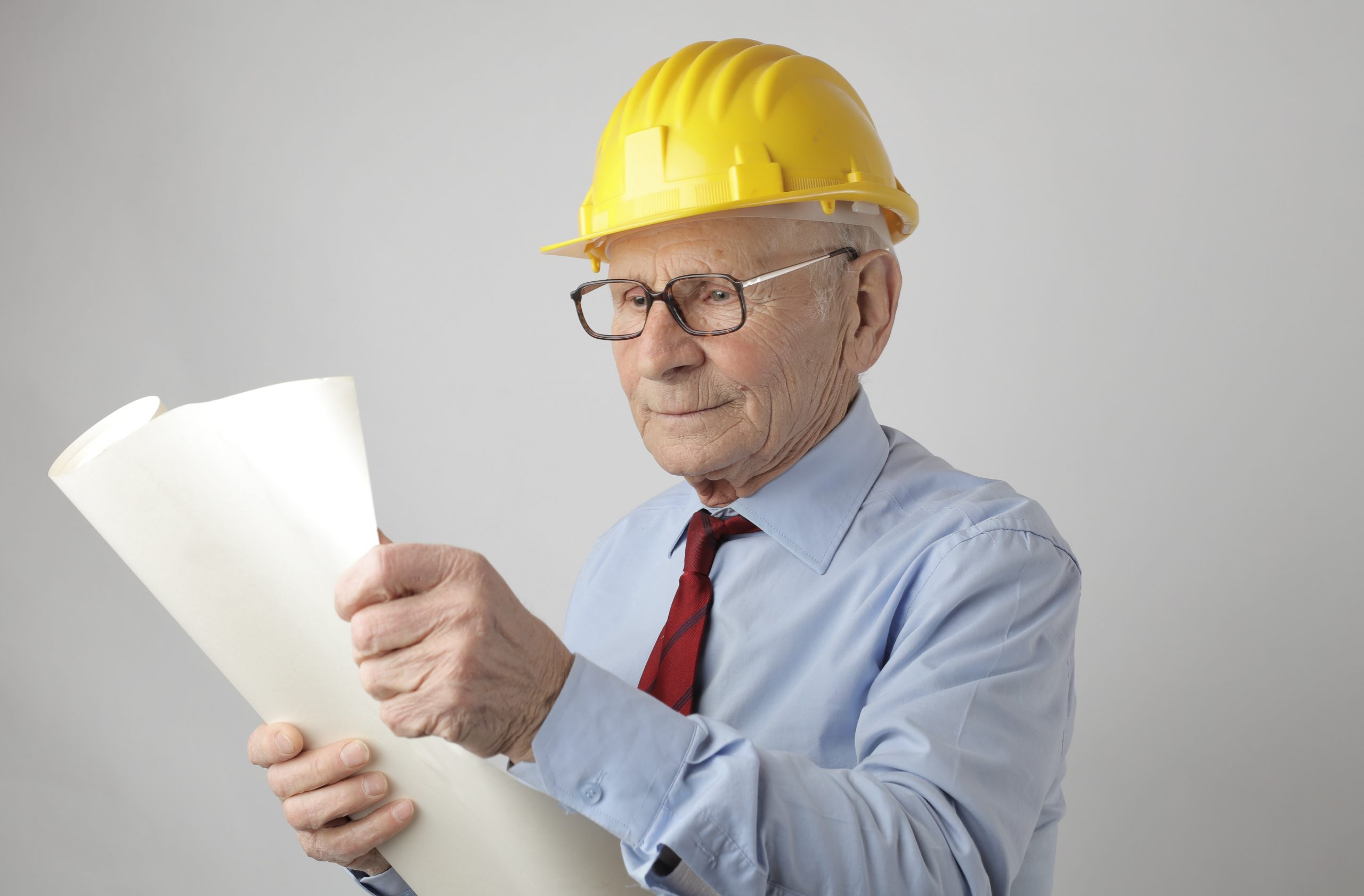man in shirt and tie with a hardhat looking at papers