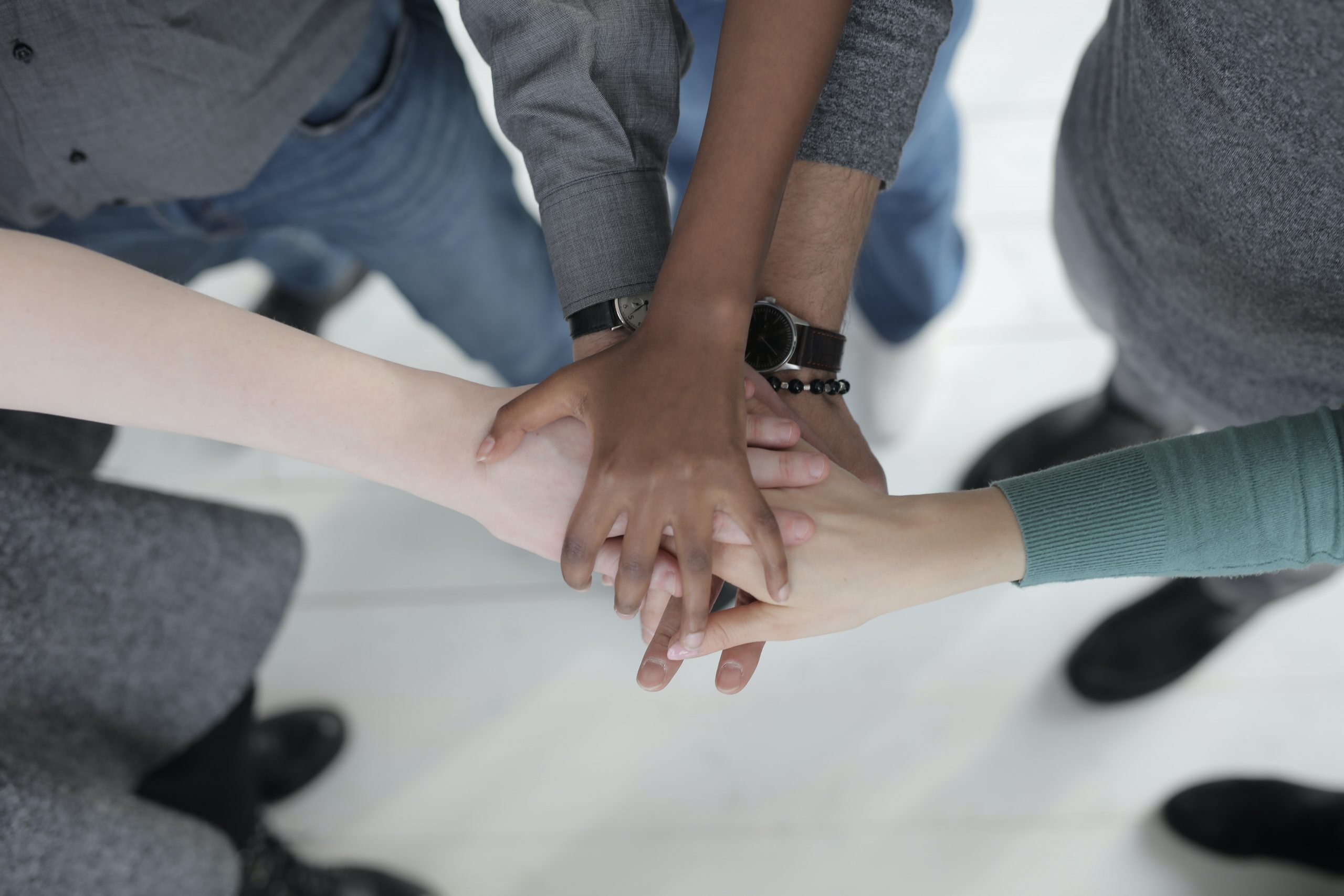 a group of people with hands on top of each other's hands as if to make a cheer